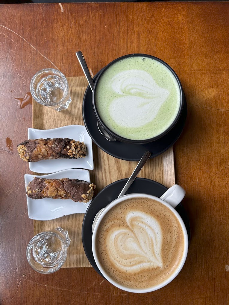 Verse koffie met latte art en lekkernijen op een houten tafel